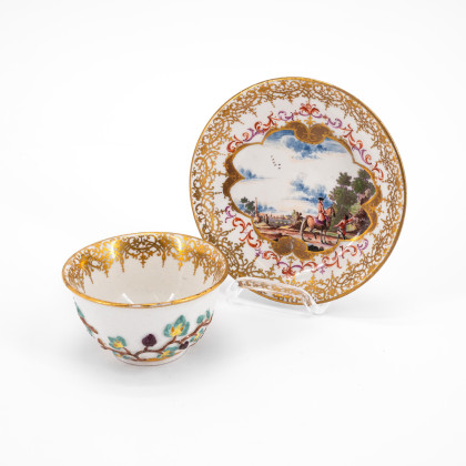 PORCELAIN TEA BOWL AND SAUCER WITH LANDSCAPE CARTOUCHES AND APPLIED VINE LEAVES DECOR