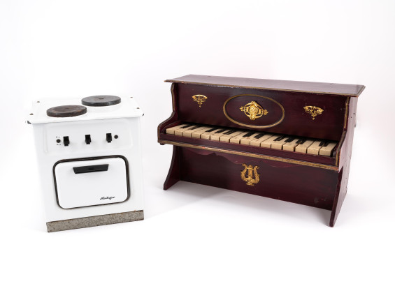 TOY PIANO MADE OF WOOD, BRASS AND PLASTIC AND A DOLL'S COOKING STOVE MADE OF SHEET METAL WITH ENAMEL DECOR