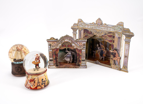 ENSEMBLE OF TWO PAPER THEATRES AND TWO SNOW GLOBES AS MUSIC BOXES MADE OF GLASS, PLASTIC, METAL, WOOD AND PAPER